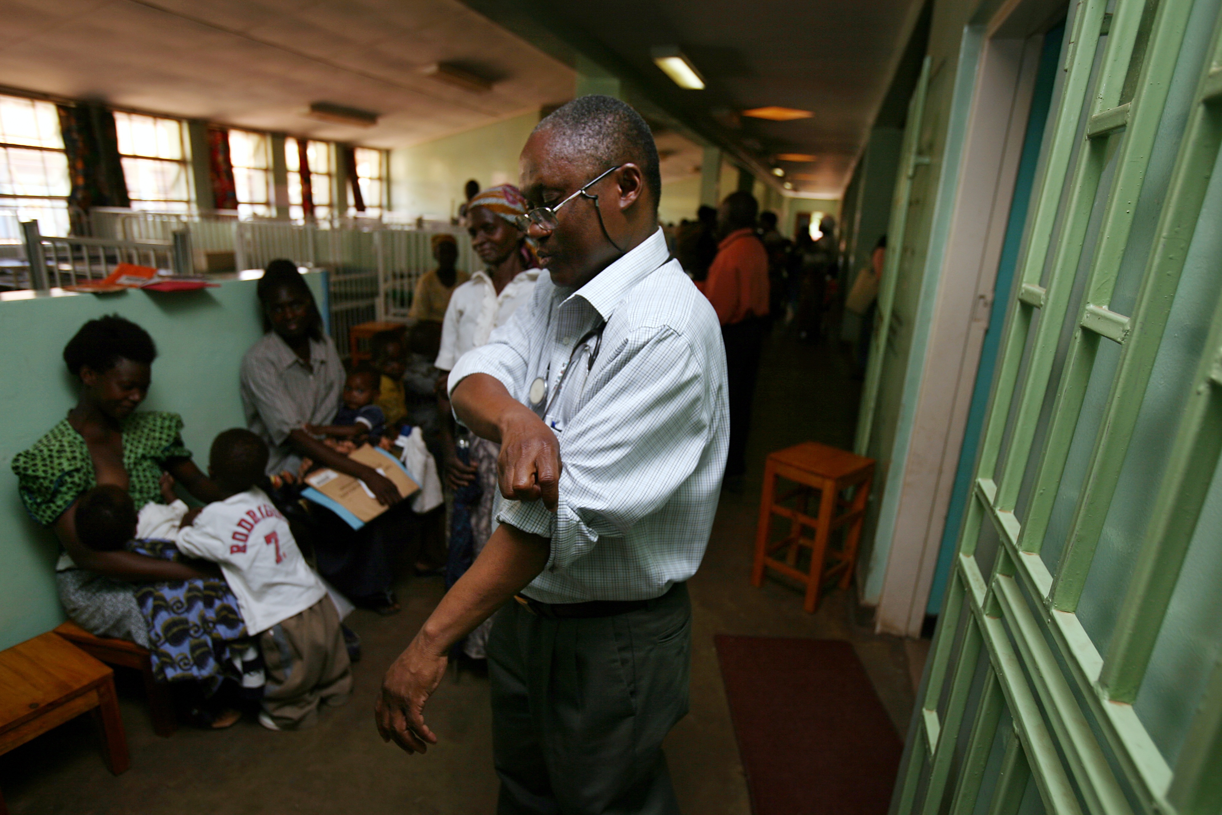 Doctor in collared shirt rolling up sleeves preparing to see patients.